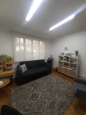 Un box de atención para niños, con un sofá y estanterías con juguetes y libros.