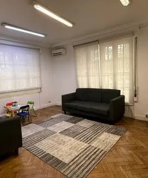 La sala de espera desde otro ángulo, con una mesa infantil junto a los sofás y la chimenea al fondo.