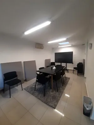 La sala de reuniones del equipo, con una mesa larga, una pantalla y un piano al fondo.